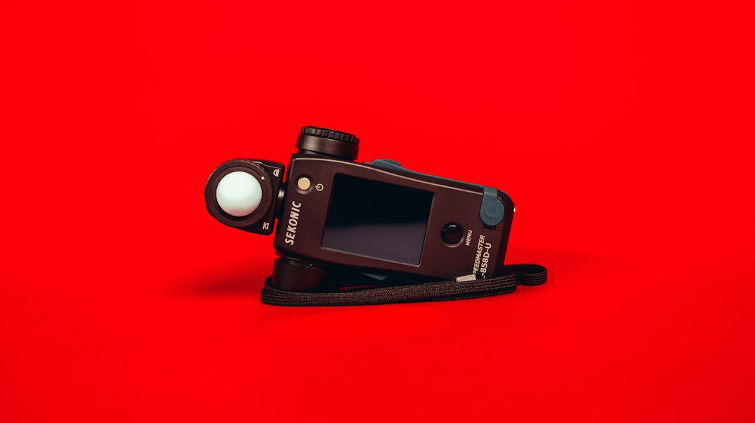 Camera on a tripod photographing a classic car in a studio