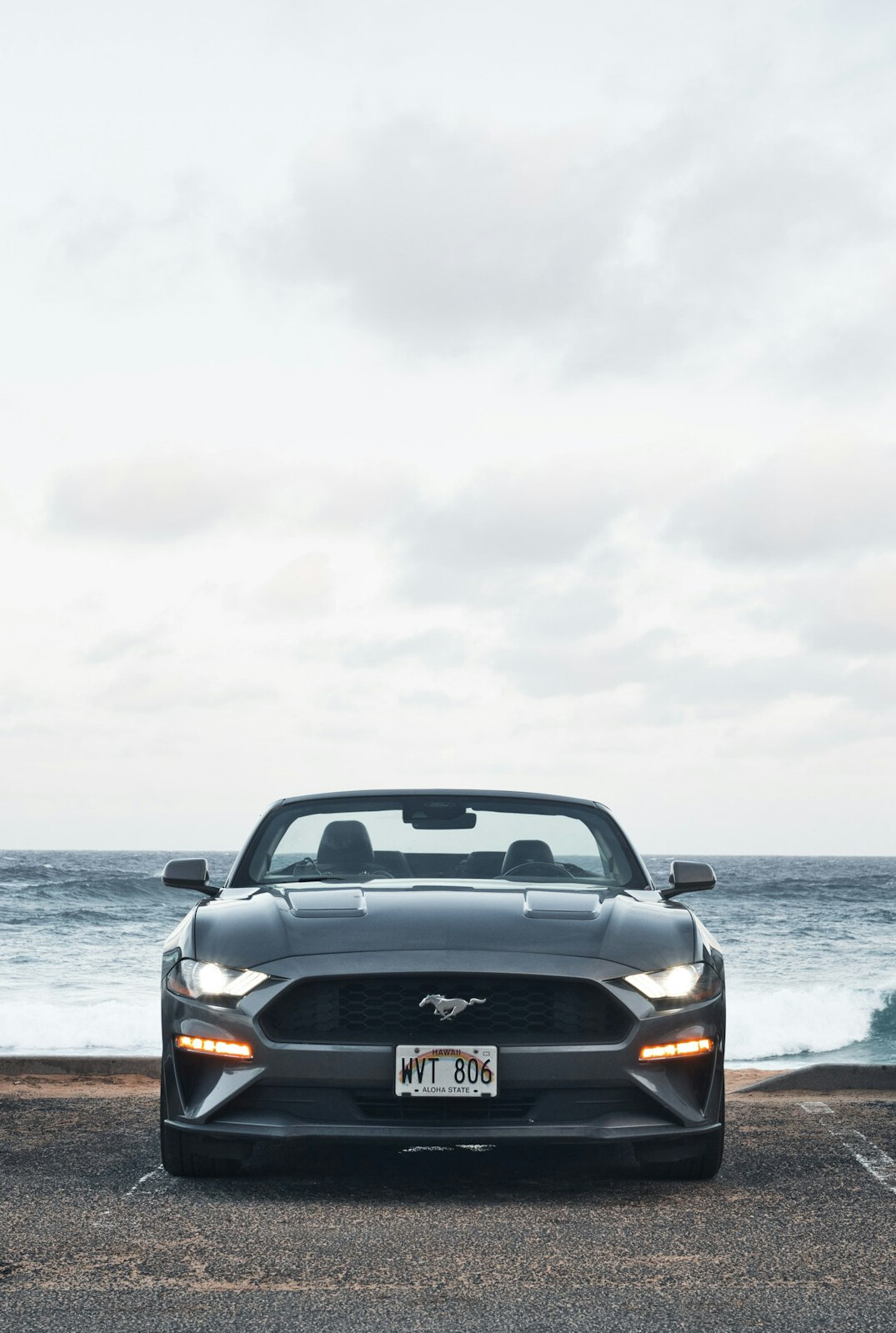 Luxury convertible car parked near a beach at sunset