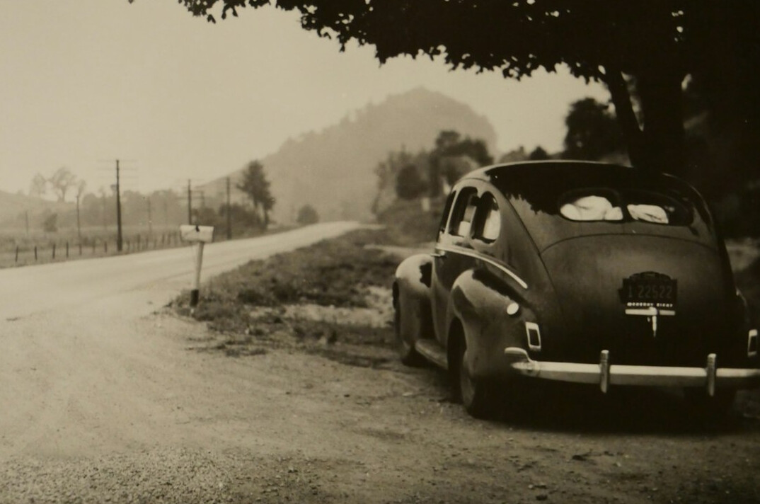 Vintage car driving through a rural countryside road