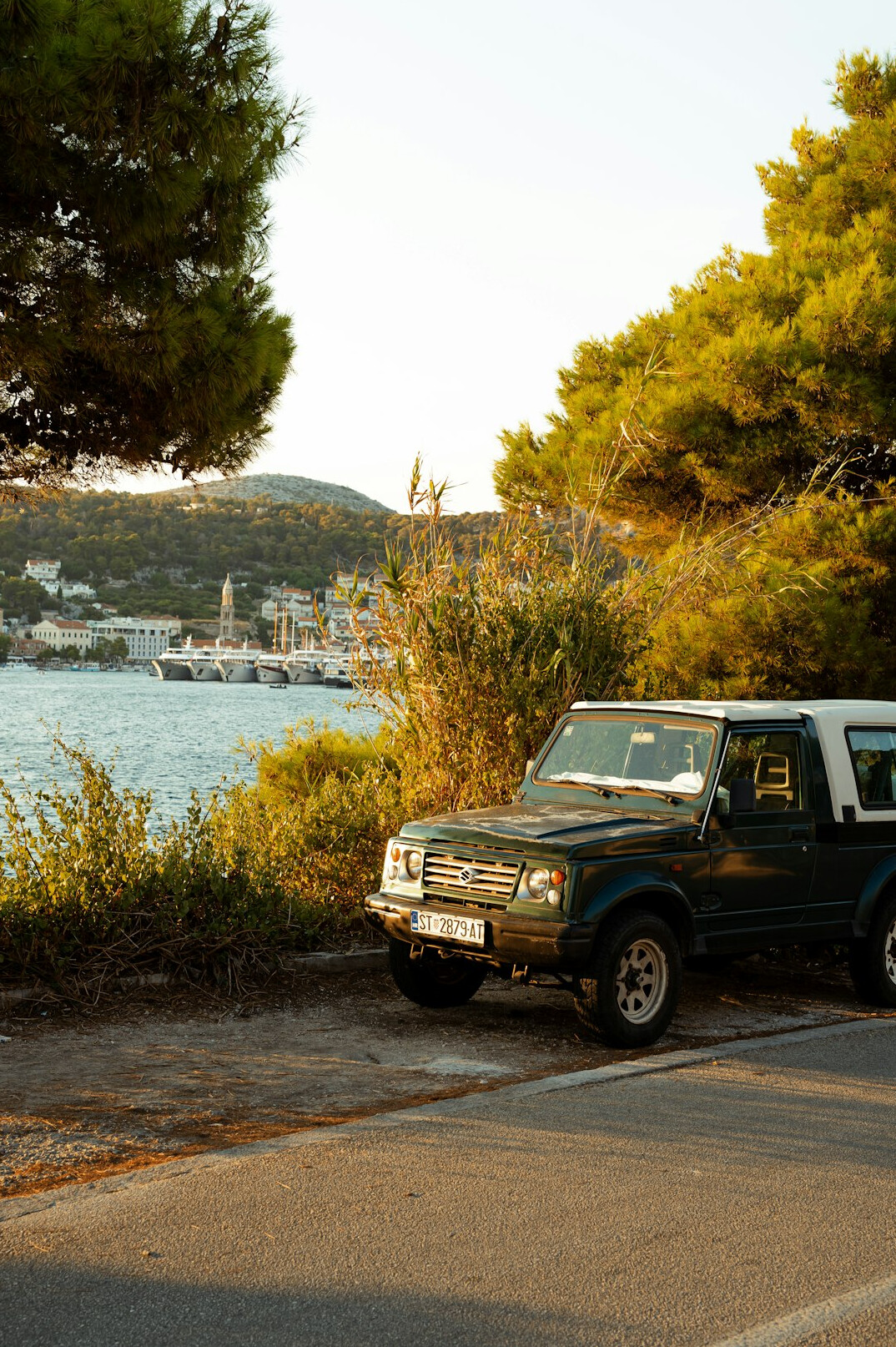 Classic sports car driving on a coastal road at sunset