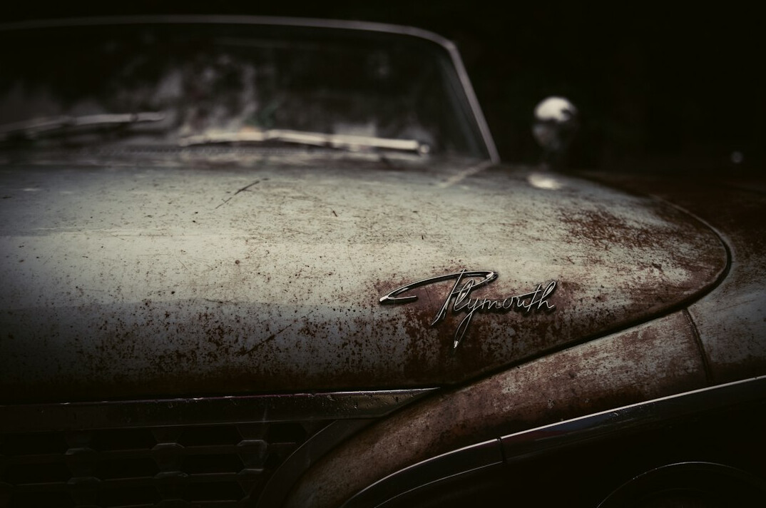 Close up of a chrome vintage car emblem covered in dust